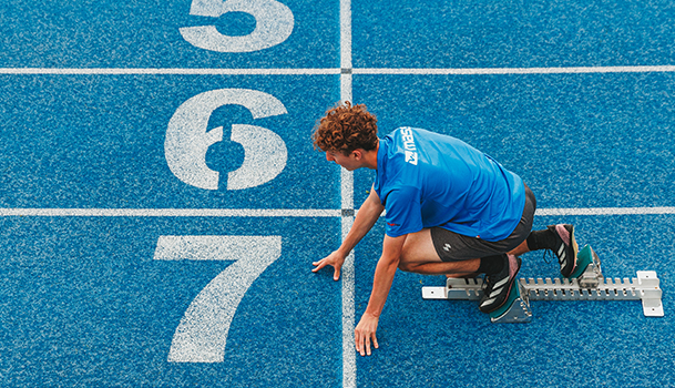 Personne se préparant à sprinter sur un terrain d'athlétisme