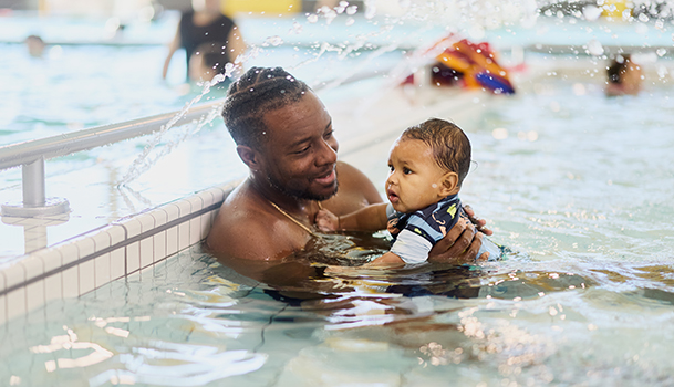 Un père avec son bébé dans les bras dans le bassin de bains libres du Complexe aquatique de Laval