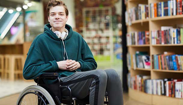 Un adolescent en chaise roulante dans une bibliothèque